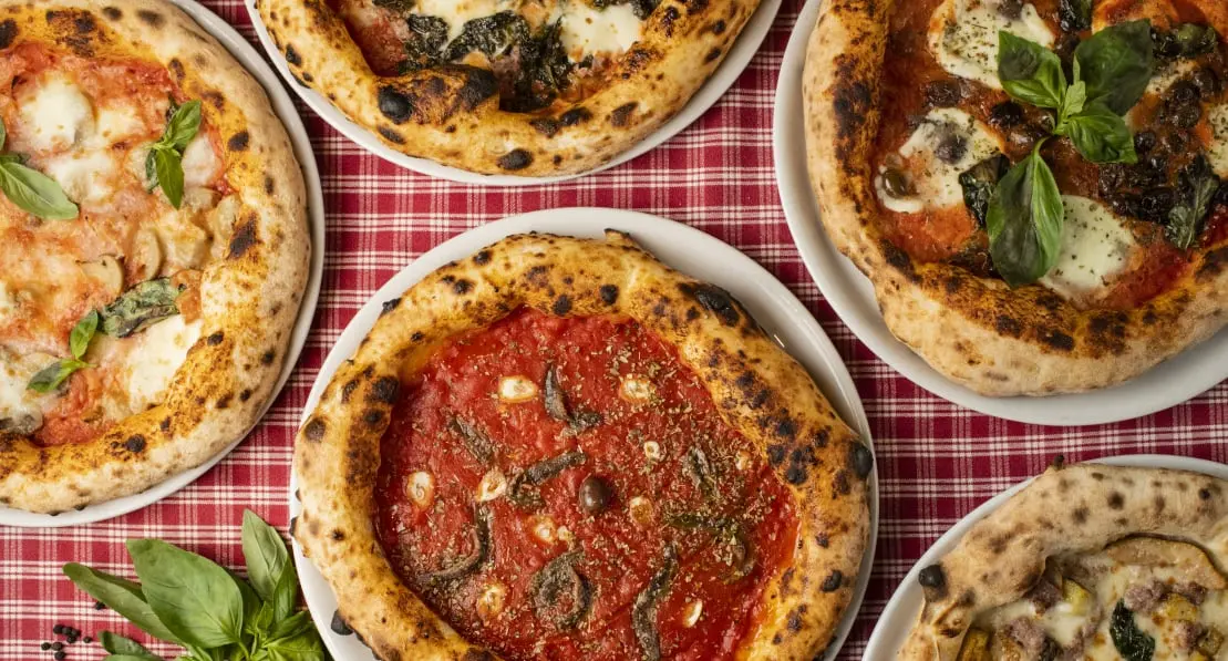 Neapolské pizzy na stole s červeným ubrusem